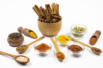 Assortment of spices in glassware and woodware close-up isolated on white background.