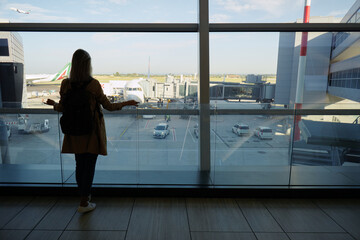 Traveling concept. Young woman in casual wear standing in international airport terminal waiting...