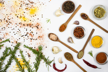 Assortment of oriental spices and herbs in glass and wooden dishes on white background.