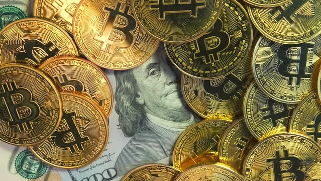 Golden shiny bitcoin crypto currency coins on US 100 dollar bills rotate close up. Virtual money coin and American dollar cash. 