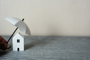 Hand use white umbrella cover home model with copy space. House, real estate, property insurance...