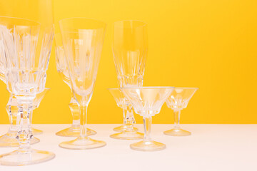 Vintage crystal glasses in front of yellow background. Place for text.
