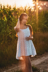 Young beautiful woman in white dress in corn field.