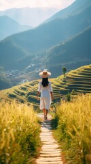 Rear view of a Vietnamese girl in a long white dress and hat walking on a mountain and rice terraces on a farm. - obrazy, fototapety, plakaty