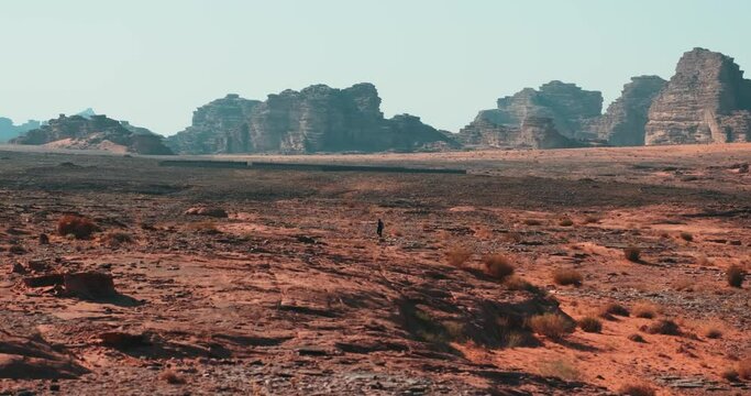 Man hiking in the desert surrounded by mountains