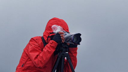 Photographer in red jacket in cold rainy weather.