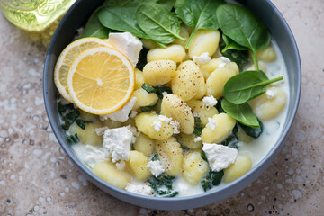 Middle close-up of potato gnocchi with spinach and feta served in a grey bowl, horizontal shot,...