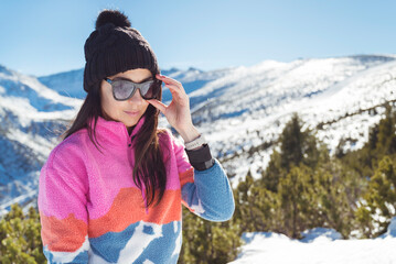 Beautiful brunette woman wearing sunglasses in the winter mountain  