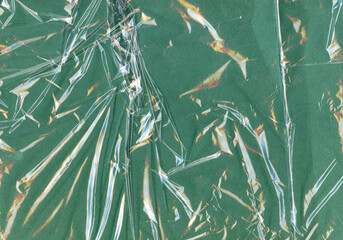 Transparent crumpled plastic textures contrasted against green background. Cellophane grungy...