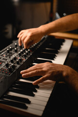 Focus on the foreground as a musician presses the keys of a professional synthesizer with one hand