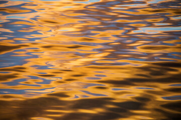 Pattern of water surface ripples merged with blue and golden color from rising sun