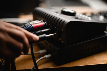 Close up side view of male hand inserting cable into jack of audio interface