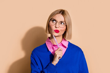 Portrait of focused intelligent person pen touch chin look empty space contemplate isolated on beige color background