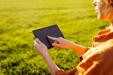 A woman farmer with a modern tablet in green field. Innovative smart farm system technology, agricultural management.