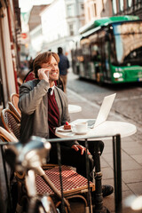 Mature man enjoying a coffee in a cafe while talking on the phone