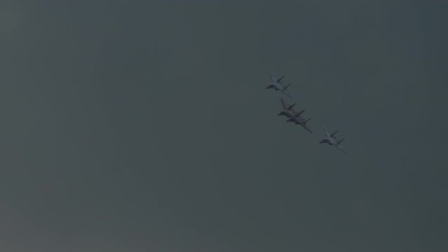 Jet fighters flying over the clouds, bottom view. Demonstration air show of military equipment