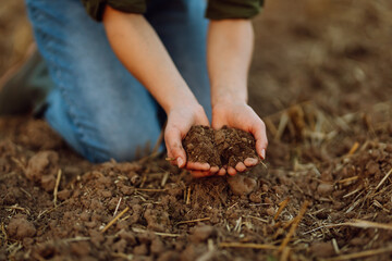 Farmer holding soil in hands close-up. Organic gardening, agriculture. Cultivated dirt, earth, ground, brown land background, nature. 