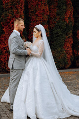 Fototapeta premium Wedding couple on a walk in the autumn park. The bride in a beautiful white dress. Love and relationship concept. Groom and bride in nature outdoors