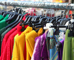 clothing stall with many clothes hanging on racks selling both new and used vintage clothes