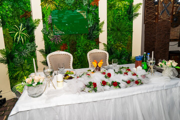 A festive and beautifully decorated wedding table. Decorated with flowers.various bottles of drinks, beautiful dishes, salads and sliced meat rolls.vegetable slicing