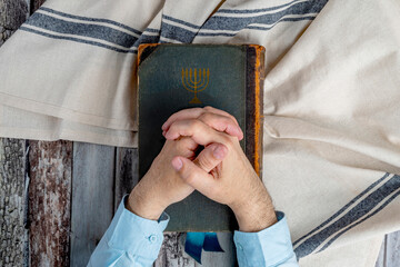 Hands and Old Book Talmud. Hebrew Rabbinic Judaism, Jewish religious law. Torah, Hebrew Bible. Menorah on a dark cover. Holy Scripture containing the word of God. Antique edition, vintage worn paper