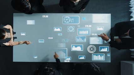 Top down aerial of collaborate professional diverse business people discuss marketing strategy with hologram of marketing data analysis graph, diagram or financial profit investment plan. Directorate.