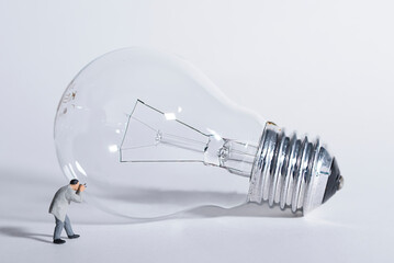 Photography of miniature people and toy figures, a photographer takes a photo of a light bulb, - obrazy, fototapety, plakaty