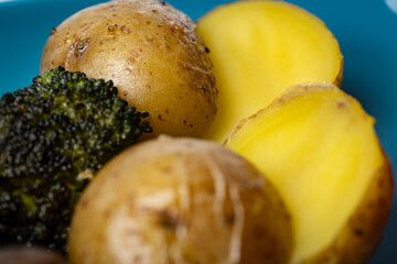 Two halved sautéed fresh potatoes on a plate next to roasted broccoli crown