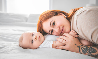Fototapeta na wymiar young beautiful mother with a baby boy on the bed at home