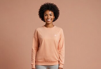 Obraz na płótnie Canvas A smiling woman with an afro wears a casual peach sweatshirt, exuding a relaxed and comfortable style.