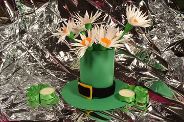 Green leprechaun hat with white flowers on silver background.
