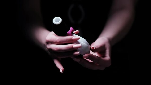 Vibrator in the shape of a penguin. Vacuum-wave clitoral stimulator in the hand of a girl on a black background. Sex Shop Products, Adult Gifts for Couples, Adult Store
