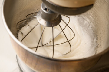 Whipped cream in a stand mixer with a whipping attachment