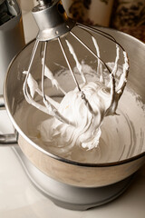 White cream on the whipping attachment of a stationary mixer
