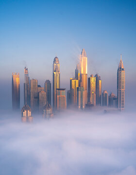 Aerial view of Dubai Marina with Cayan Tower and foggy skyline, Dubai, United Arab Emirates.