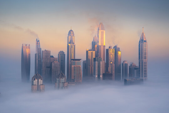 Aerial view of Dubai Marina with Cayan Tower emerging from the mist, Dubai, United Arab Emirates.