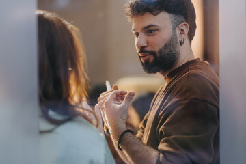 A bearded man with earrings engaging in a casual conversation with an unseen female, conveying a...