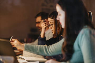 Focused colleagues collaborating on project late at night in office.