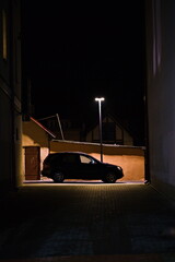 Ciemny profil samochodu w uliczce oświetlonej światłem latarni, miasto nocą
