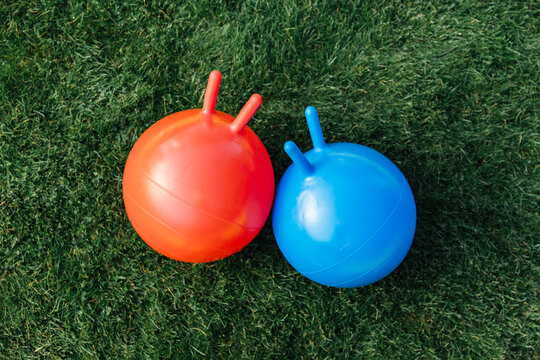 childhood, leisure and toys concept - two bouncing balls or hoppers on grass
