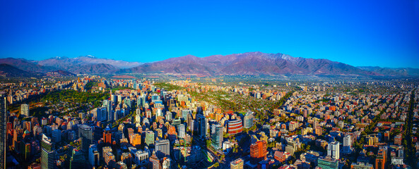 Panoramic View of Santiago de Chile. In a panoramic photo of Santiago, Chile, on a sunny summer day, the cityscape unfolds with the snowless Andes mountains in the background, creating a picturesque s