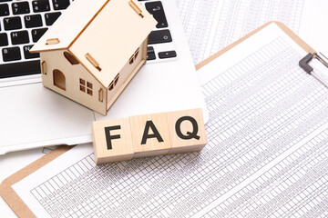 FAQ - word on wooden cubes on a white background with a table, laptop keyboard and a small wooden...