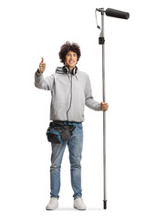 Boom operator with headphones holding a microphone and gesturing thumbs up
