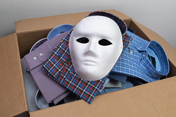 A white mask lies on shirts in an open cardboard box, a concept on the theme of counterfeit...