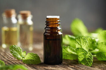 A brown bottle of aromatherapy essential oil with peppermint leaves