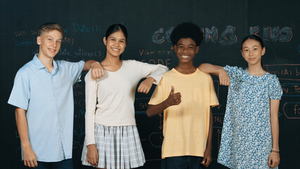 Group of smart multicultural teenager looking at camera at blackboard. Happy diverse children...