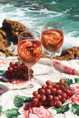 Romantic day by the sea with rose wine in wine glasses and a beautiful seascape and rocky beach