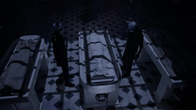 Two doctors standing in fron of a corpse in the morgue and ready to execute an autopsy