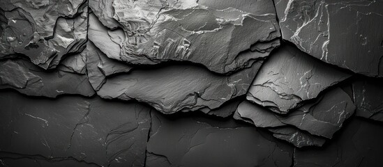 A close-up view of a dark grey black slate rock wall, showcasing its rugged texture and natural formation.