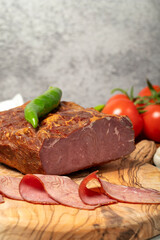 Smoked cold beef sirloin and slices on cutting board. Cold roastbeef slices on gray background. Close up